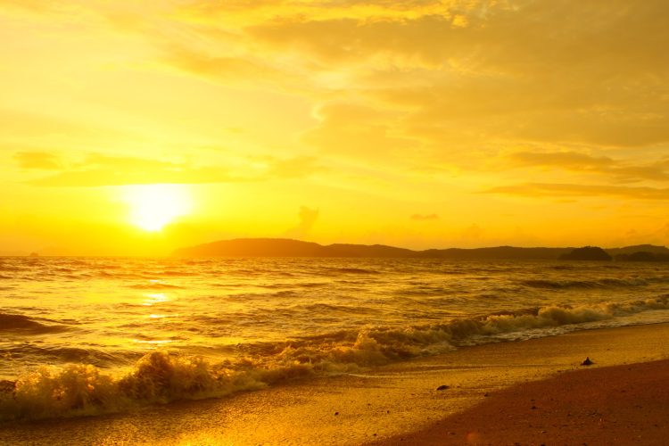 Young woman walking on beach under sunset light